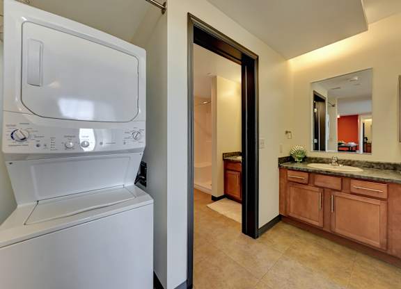 a washer and dryer in a bathroom with a sink and a mirror at Parkhaus Apartments, Lincoln, 68508