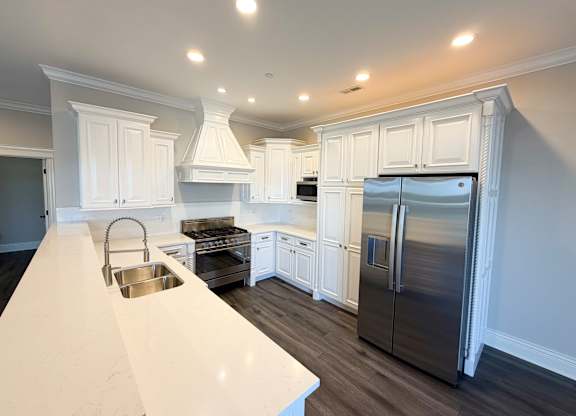 A kitchen with white cabinets and a stainless steel refrigerator.