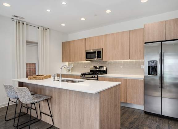 A modern kitchen with a white countertop and stainless steel appliances.
