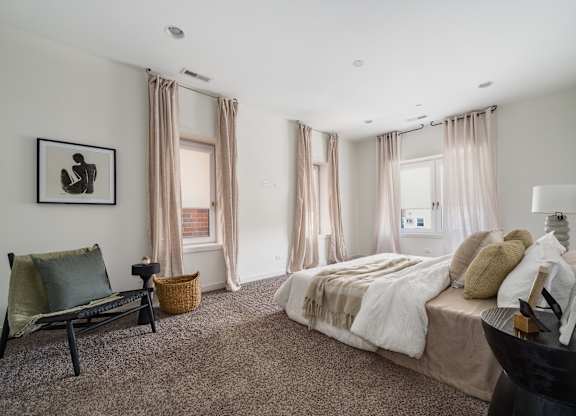 A bedroom with a large bed and a chair.