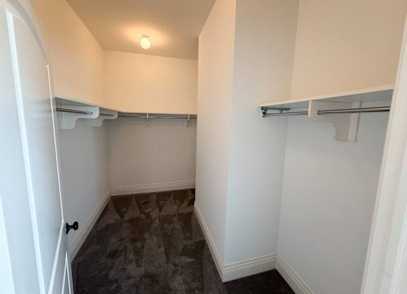 A small, empty room with a grey carpet and white walls.