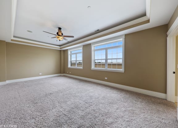 an empty living room with a ceiling fan and two windows
