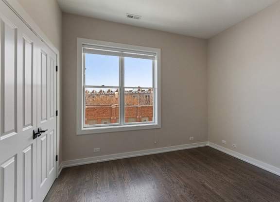 an empty living room with a window and wooden floors