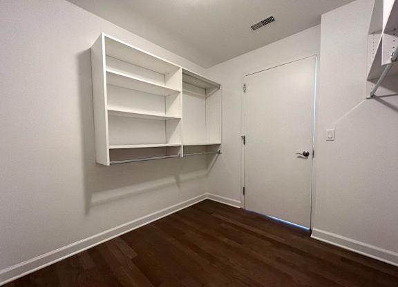 a bedroom with white walls and a closet with shelves