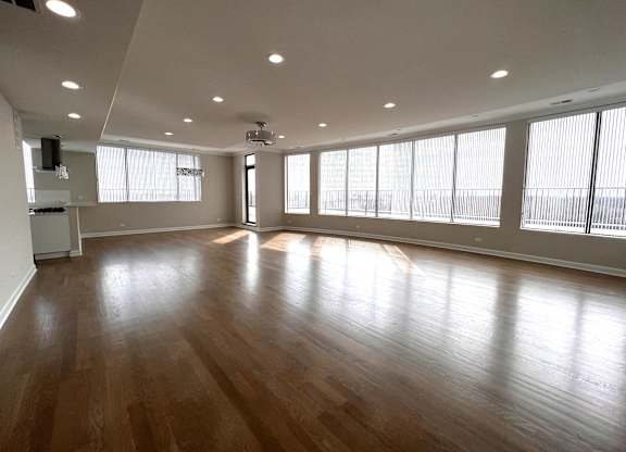 an empty living room with wood floors and large windows