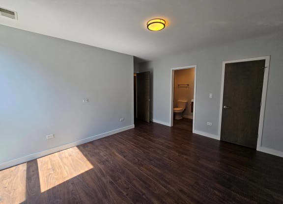 a living room with wood floors and a door to a bathroom