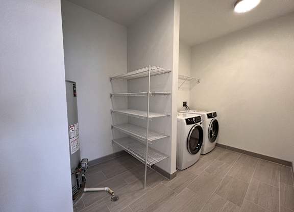 a washer and dryer in a laundry room with white walls and tile floor