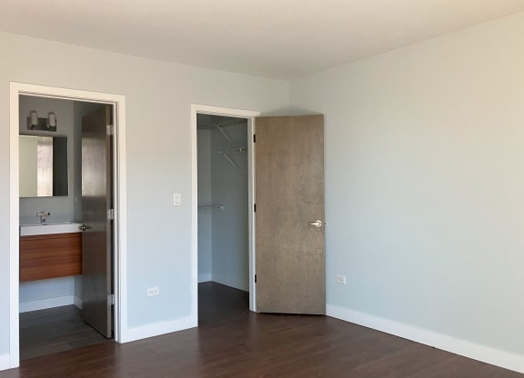 an empty room with a door to a bathroom and a mirror