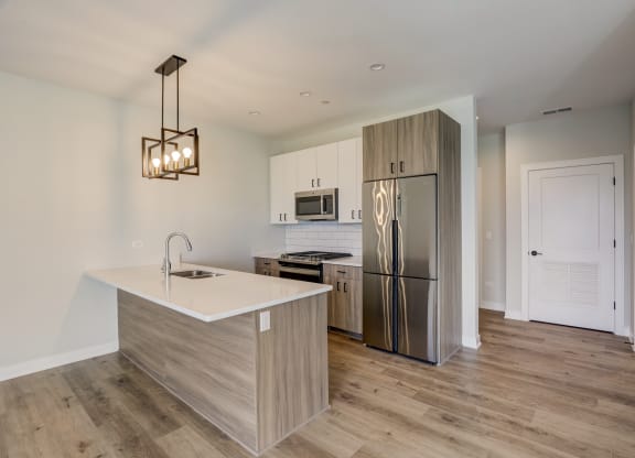 a kitchen with a large island and stainless steel refrigerator
