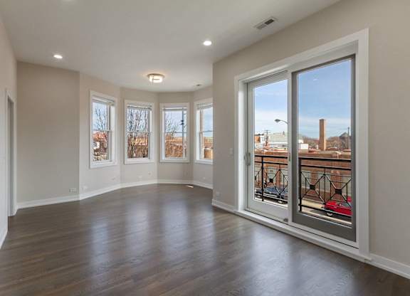 an empty living room with large windows and a wood floor