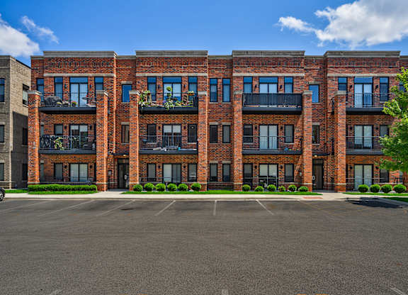A large red brick building with a parking lot in front.