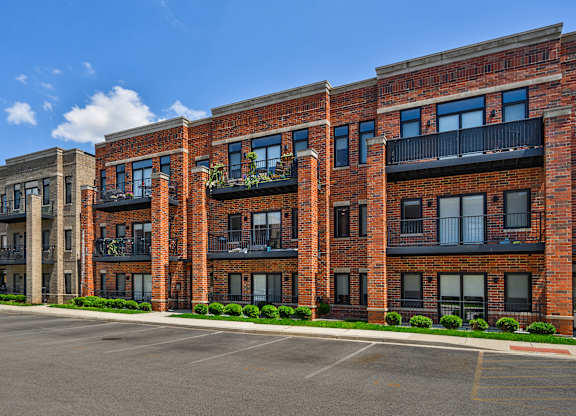 A row of red brick apartment buildings with balconies and windows.