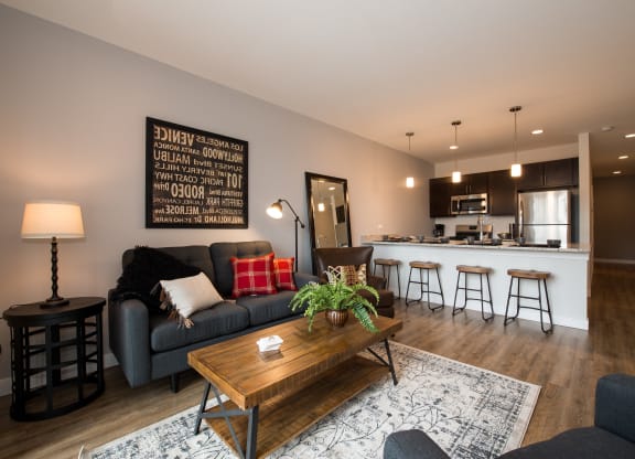 a living room with a couch and a table in front of a kitchen