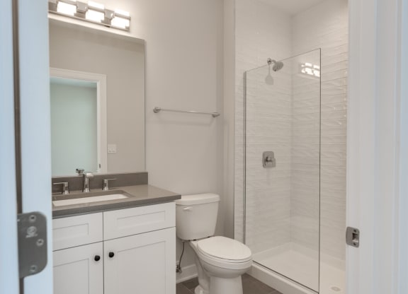 a white bathroom with a shower toilet and sink