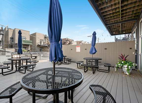 A patio with tables and chairs and umbrellas.
