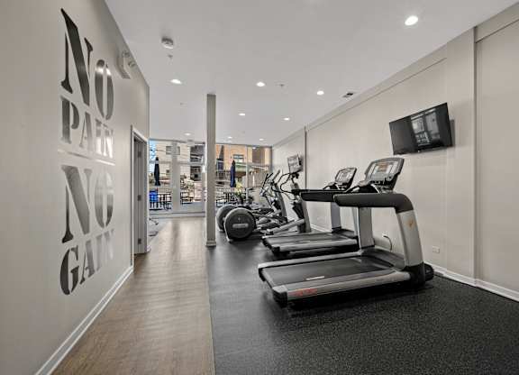 A gym with treadmills and a wall that says
