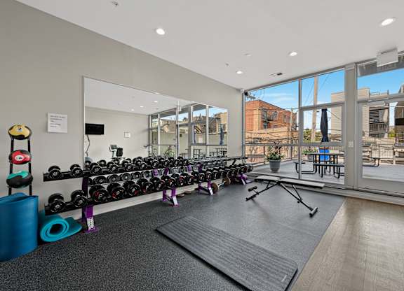 A gym with a variety of equipment including weights and a bench.