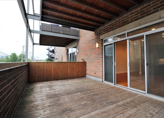 a large deck with a brick wall and sliding glass doors