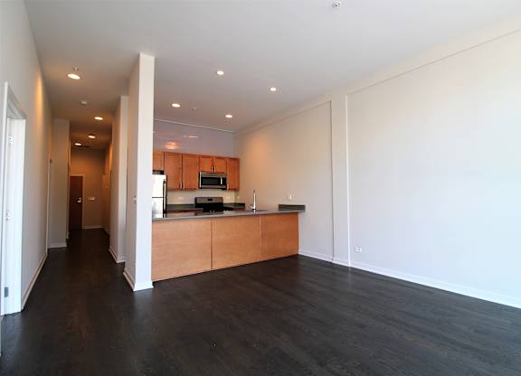 an empty living room and kitchen with wood floors and white walls