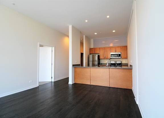a living room with wood flooring and a kitchen