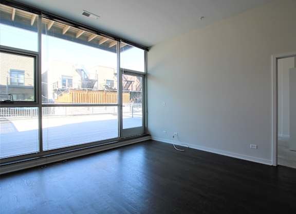 an empty living room with a large window and wood flooring