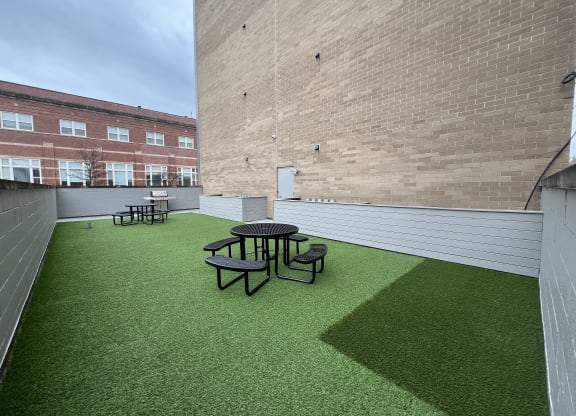 a roof deck with a table and chairs on a green lawn
