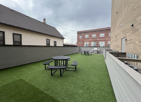a rooftop patio with a green lawn and tables