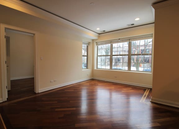 an empty living room with wooden floors and a large window