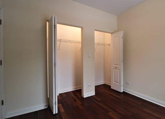 a bedroom with two closet doors and a hard wood floor