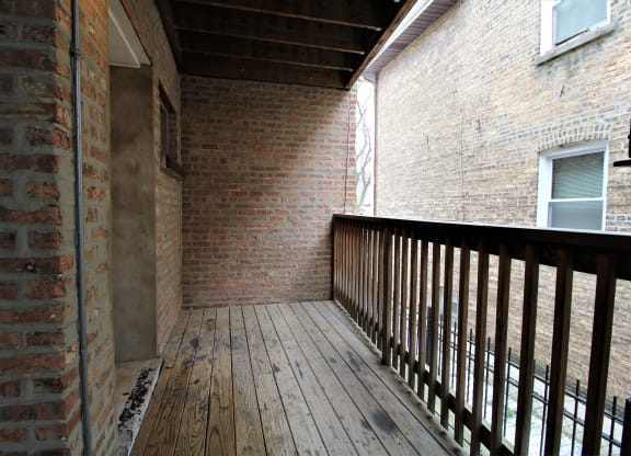 the back deck of the house has brick walls and a wooden railing