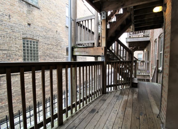 a balcony with wooden floors and stairs in a brick building