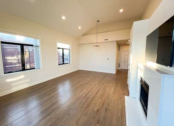 A spacious living room with wooden flooring and a fireplace.