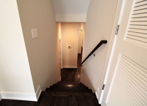 a stairwell in a home with wood floors and white walls and a white door