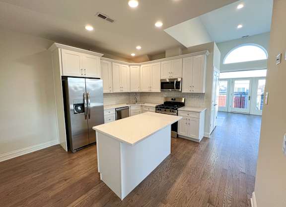 A kitchen with white cabinets and a white island.