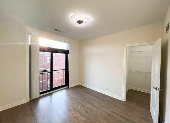 A room with a sliding glass door leading to a balcony.