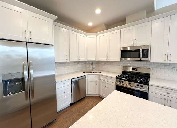 A kitchen with white cabinets and a stainless steel refrigerator.