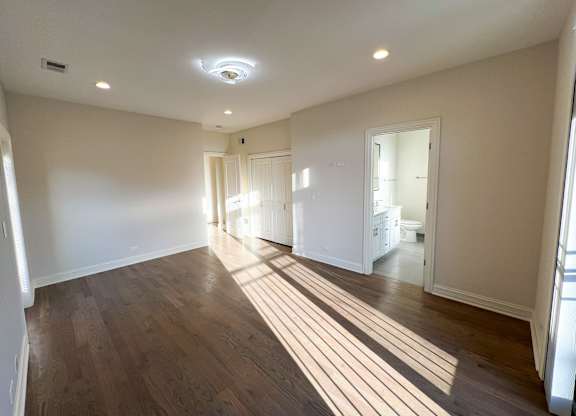 A spacious room with wooden floors and white walls.