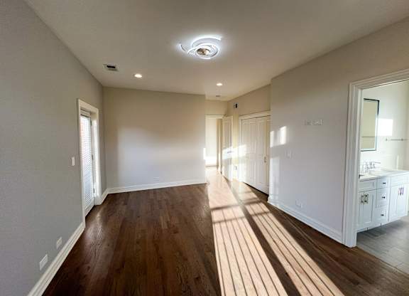 A spacious room with wooden floors and white walls.