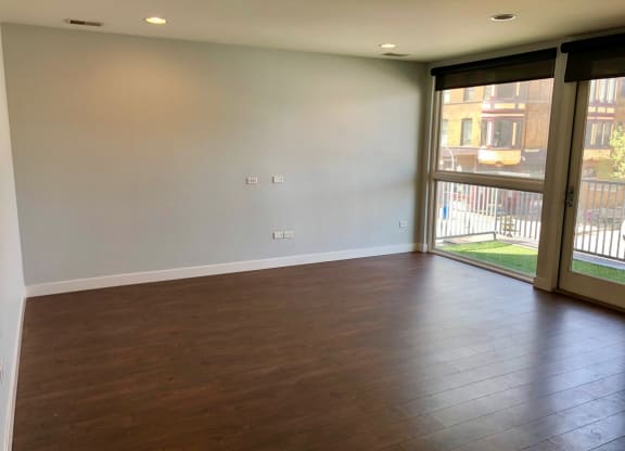 an empty living room with wood floors and a sliding glass door