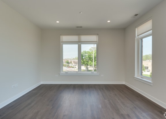 an empty living room with wood floors and a window