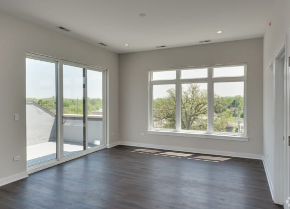 an empty living room with large windows and a balcony