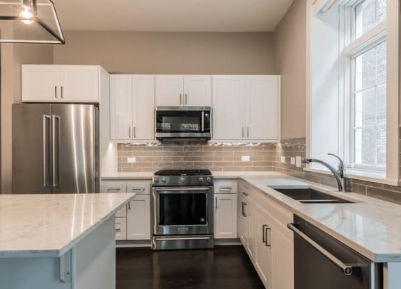 a kitchen with white cabinets and stainless steel appliances