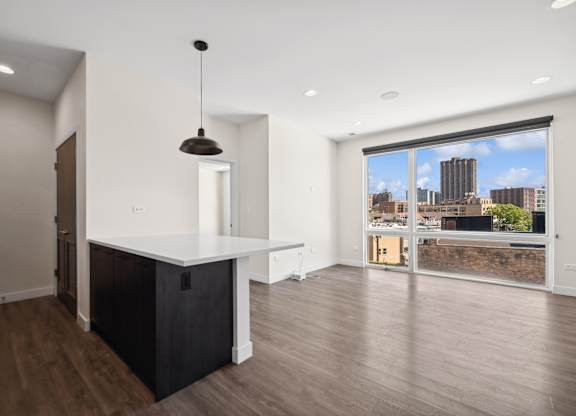 Open kitchen and living room at Highpoint Buena Park on Broadway featuring modern finishes, stainless steel appliances, and floor-to-ceiling windows with city views in a Chicago apartment
