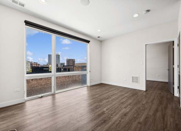 Living room at Highpoint Buena Park on Broadway with modern hardwood floors, large windows, and open sightlines to the kitchen in a contemporary Buena Park apartment near the Sheridan Red Line Station in Chicago