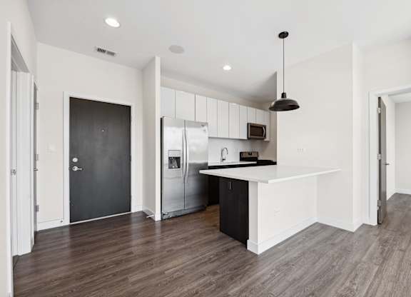 A modern kitchen with a black door and a white countertop.