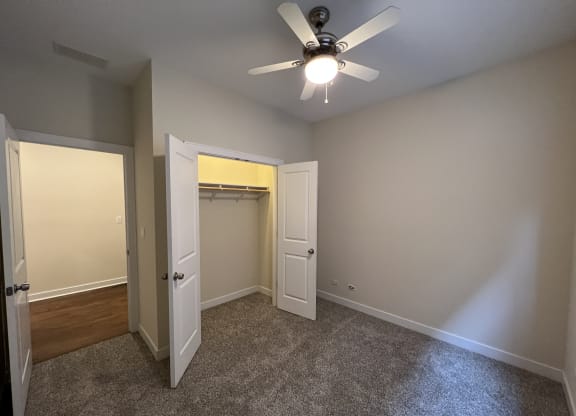 an empty bedroom with a ceiling fan and a closet
