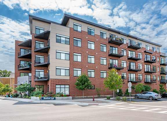 A large apartment building with balconies and a street in front.
