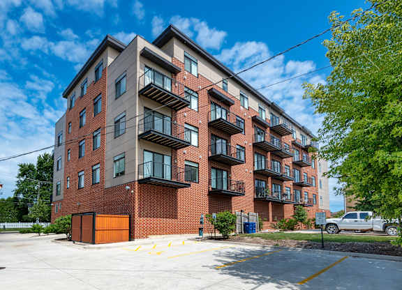 A large red brick apartment building with a parking lot in front.