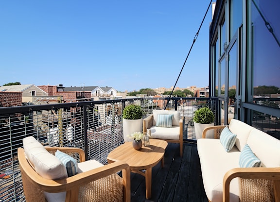 a balcony with white chairs and a wooden table