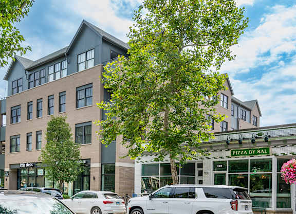A building with cars parked in front and a sign that says Pizza by Sal.